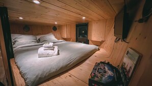 Un dormitorio de cabaña de madera acogedor con cama, almohadas y mesita de noche.