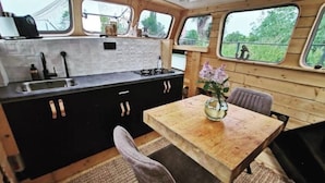Una cocina compacta con una mesa y sillas de madera, un lavamanos y una ventana con vistas a zonas verdes.