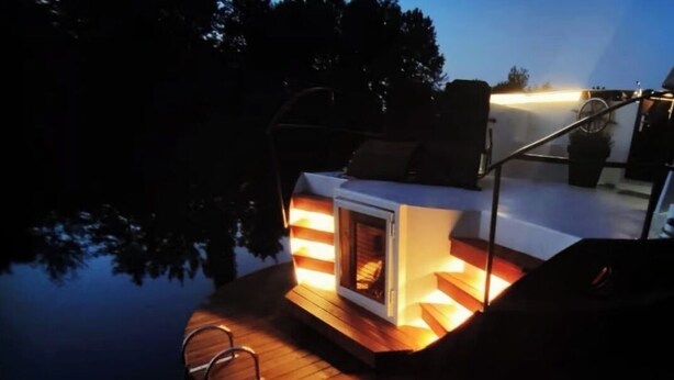 Terraza de madera con chimenea integrada y zona de estar al aire libre.