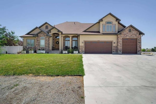 A two-story house with a stone facade, a front garage, and a well-maintained lawn.