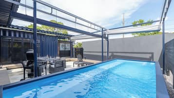 Relax by the pool, surrounded by an outdoor space with a barbecue grill and dining area.