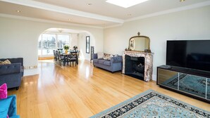 A spacious living room with a fireplace, a television, and a dining area with a view of the city.