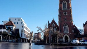 A historic church with a tall clock tower, surrounded by modern buildings and a pedestrian area. - Studio Flat in London (London)