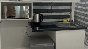 A compact kitchen with a microwave, coffee maker, sink, and a small refrigerator. - Studio Flat in London (London)