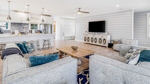 A spacious living area with a wooden coffee table, grey sofas, and a flat-screen TV mounted on the wall. - Luxe Palmilla Beach home with Gulf view, guest suite, pool access, walk to beach (Port Aransas)