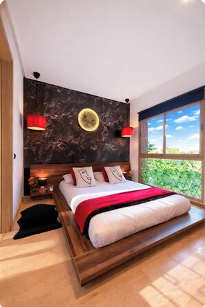 A modern bedroom with a large bed, a view of greenery outside, and a unique wall design.