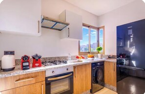 A modern kitchen with a gas stove, a dishwasher, a washing machine, and a Samsung refrigerator.