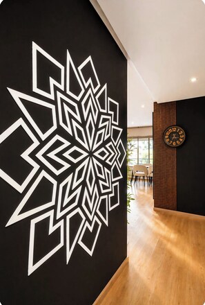 A modern interior with a geometric wall design, a wooden floor, and a round wall clock.