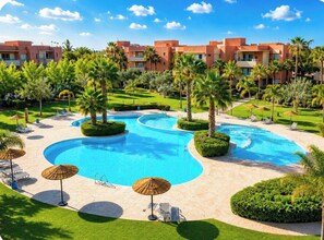 A resort with a large swimming pool, palm trees, and a building with balconies.