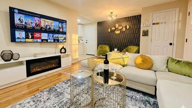 A modern living room with a flat-screen TV, a fireplace, a glass coffee table, and a sofa with cushions. - Denver Ultimate Group Getaway: Mini-Golf, Hot Tub, Fire Pit, Games & Playground (Denver)