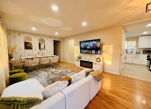 Una sala de estar moderna con un sofá, un televisor y un comedor con sillas y una mesa.