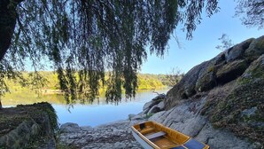 Una barca a remi su un sentiero di pietra vicino a un lago calmo, circondata da rocce e alberi.