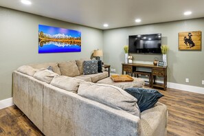A living room with a large sectional sofa, a flat-screen TV mounted on the wall, and a wooden coffee table. - Laramie Gem < 1/2 Mi to University of Wyoming! (Laramie)