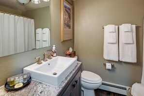 A bathroom with a large sink, two faucets, a mirror, and a toilet. There are towels hanging on the wall and a framed picture above the mirror. - Laramie Gem < 1/2 Mi to University of Wyoming! (Laramie)
