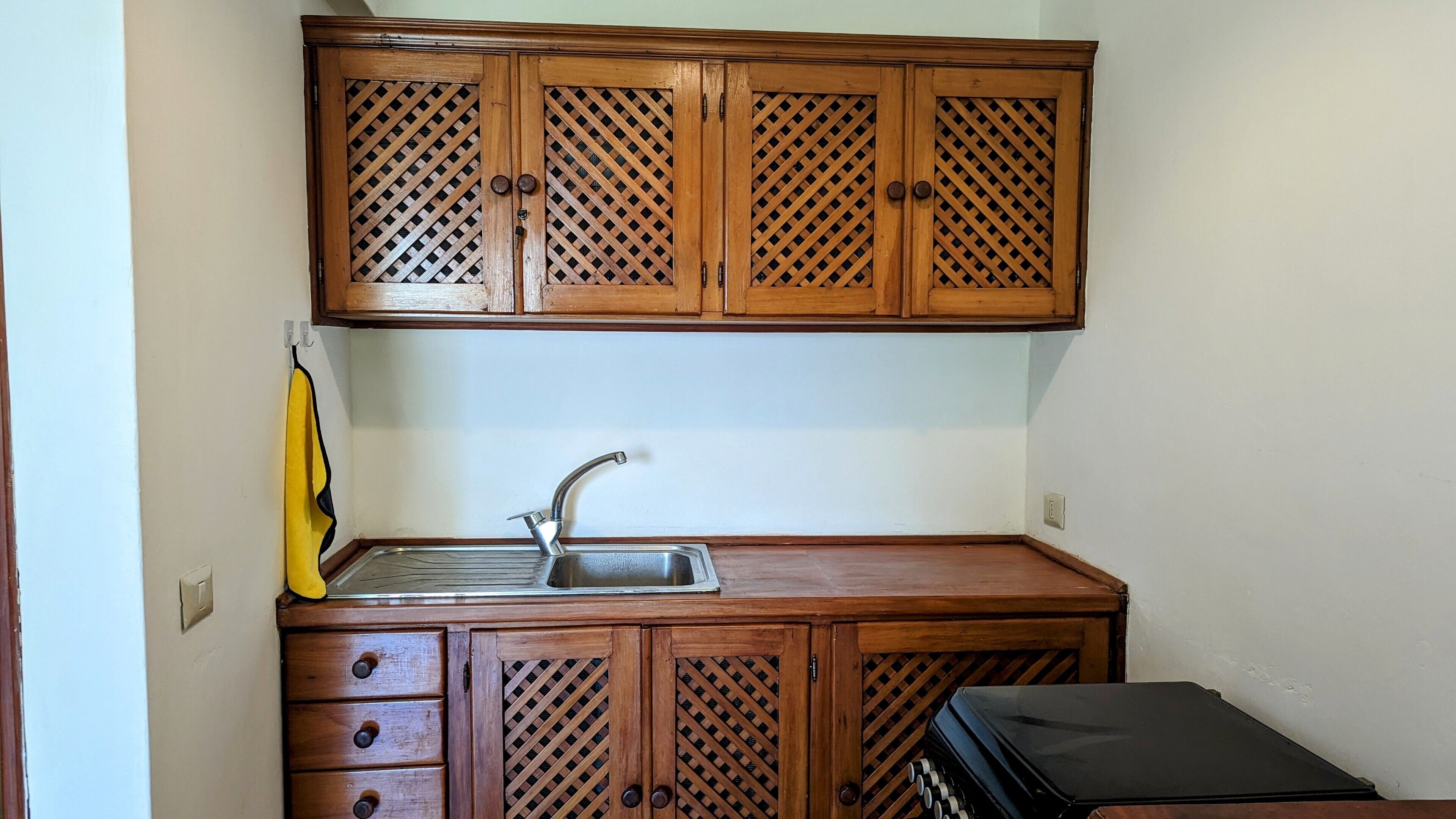 A compact kitchen with wooden cabinets, a sink, and a countertop.