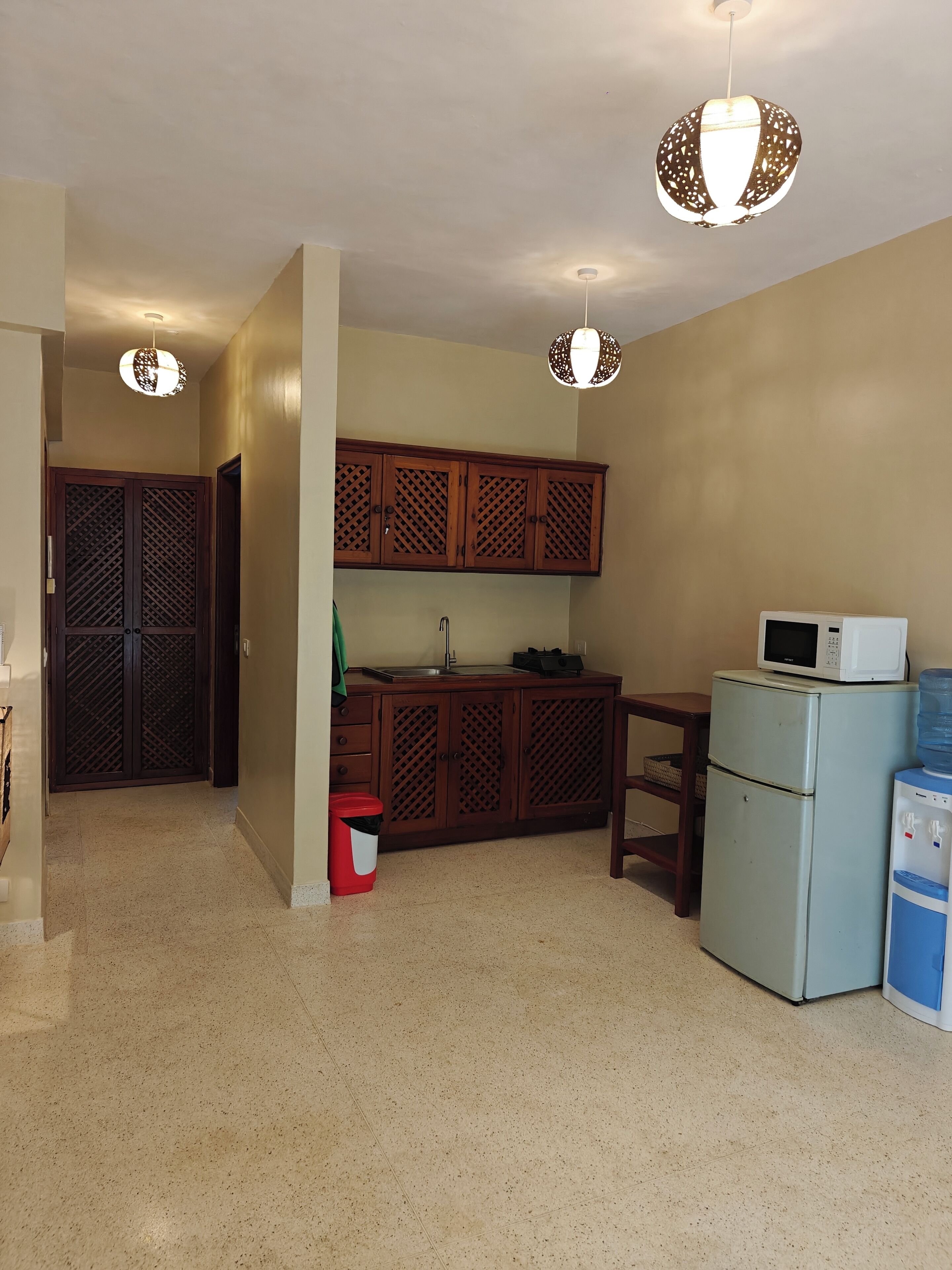 A compact kitchen with wooden cabinets, a sink, a microwave, and a refrigerator.