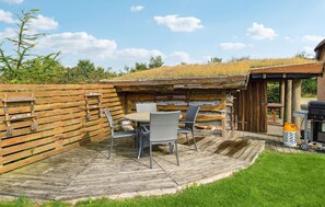 A rustic outdoor seating area with a wooden table and chairs, a grill, and a wooden fence. - 3 bedroom beautiful home in Tarm (Tarm)