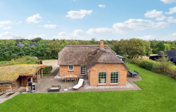 A thatched-roof house with a brick extension, a patio with outdoor furniture, and a grassy yard. - 3 bedroom beautiful home in Tarm (Tarm)