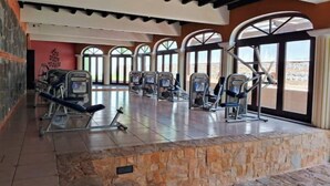 A gym with exercise equipment, large windows, and a stone accent wall. - Luxurious colonial style home! (San Pedro Las Huertas)