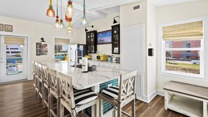 A spacious kitchen with a large island, wooden chairs, and hanging pendant lights. - Close to Everything in Gulf Shores! 5 BR house w/Private Pool (Gulf Shores)