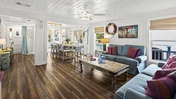 A spacious living area with a wooden floor, a dining table with chairs, a sofa, and a coffee table. - Close to Everything in Gulf Shores! 5 BR house w/Private Pool (Gulf Shores)