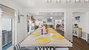 A dining area with a long table, yellow placemats, and a wooden ceiling with hanging light fixtures. - Close to Everything in Gulf Shores! 5 BR house w/Private Pool (Gulf Shores)