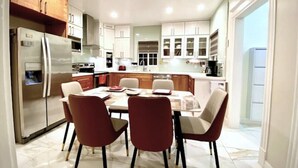 A modern kitchen with a central island, white cabinetry, and a dining area with red chairs. - CentralDowntownSanJose-Stunning, fireplace Modern Craftsman house/SAP, Airport (San Jose)