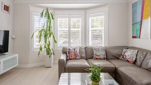 A living room with a brown leather sofa, a glass coffee table, and a large potted plant. - CentralDowntownSanJose-Stunning, fireplace Modern Craftsman house/SAP, Airport (San Jose)