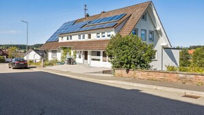 A two-story house with solar panels on the roof, a garage, and a driveway. - 1 bedroom cozy apartment in Seewald (Seewald)