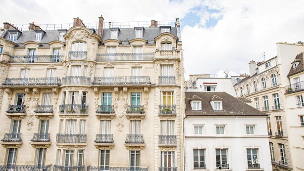 A multi-story building with ornate architectural details, including balconies with metal railings and decorative stonework. - Central Duplex Notre Dame (Paris)