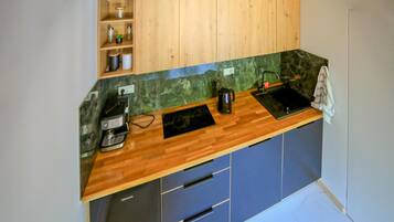 Une cuisine compacte avec des meubles en bois, un plan de travail en marbre, une machine à café et un évier.