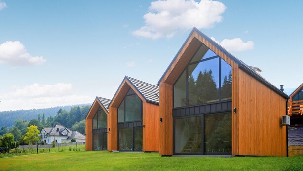 Een modern gebouw met grote ramen en een schuin dak, omgeven door gazon en bomen.
