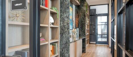 A modern library with wooden shelves, marble accents, and a clear view into the adjacent room.