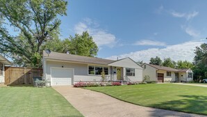 Une maison de plain-pied avec un garage à l’avant, une véranda et une pelouse bien entretenue.