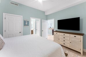 Ein Schlafzimmer mit einem großen Bett, einem an einem Holzkasten montierten Fernseher und weißen Türen.