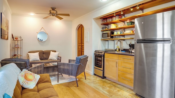 A modern kitchen with a stainless steel refrigerator, wooden cabinets, and a built-in oven. - Surfer's Paradise: Waialua Condo Steps to Beach! (Waialua)