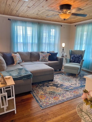 A cozy living room with a sectional sofa, a small side table, a decorative chair, and a patterned rug. - The Cajun Cottage - Downtown Cottage (Lake Charles)