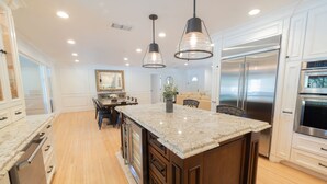 Una cocina moderna con una isla grande, electrodomésticos de acero inoxidable e iluminación colgante.