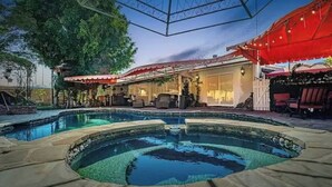 Un área de piscina con hidromasaje, mobiliario exterior y un patio cubierto.