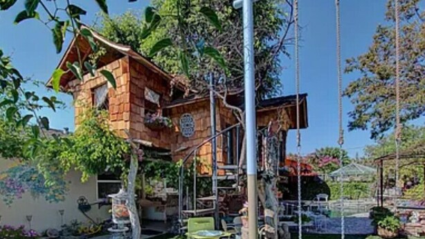 Una casa de madera rústica con un porche pequeño y un columpio.