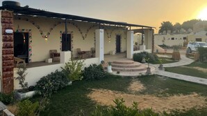 Un edificio con un patio cubierto, mobiliario exterior y un jardín ajardinado.