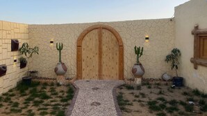 Un patio con puerta de madera, plantas en macetas y una pared de piedra.