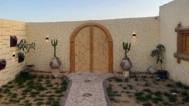 Un patio con puerta de madera, plantas en macetas y una pared de piedra.