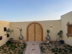Un patio con puerta de madera, plantas en macetas y una pared de piedra.