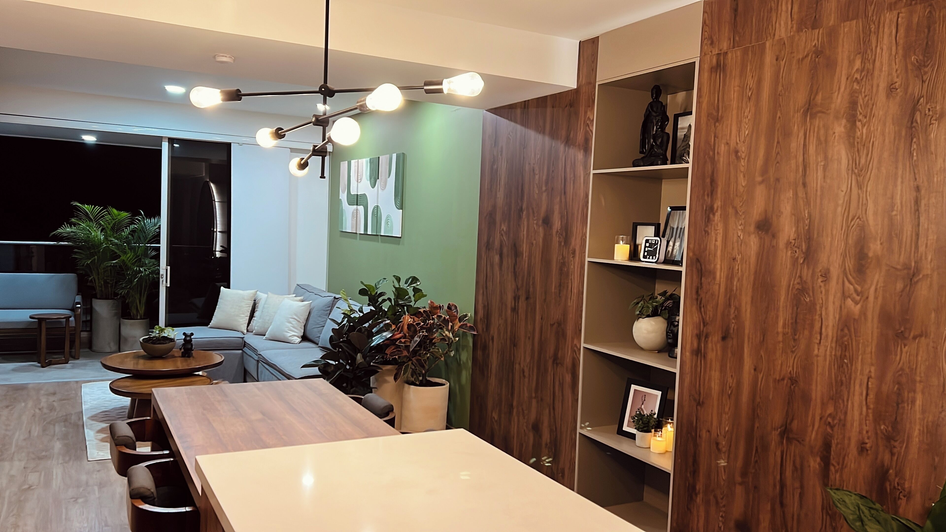 Un salon moderne avec une table à manger en bois, un canapé et un mur d’accent vert.