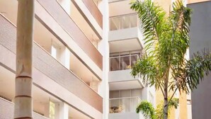 Un immeuble à plusieurs étages doté de balcons, une cour intérieure agrémentée de plantes et une architecture moderne.