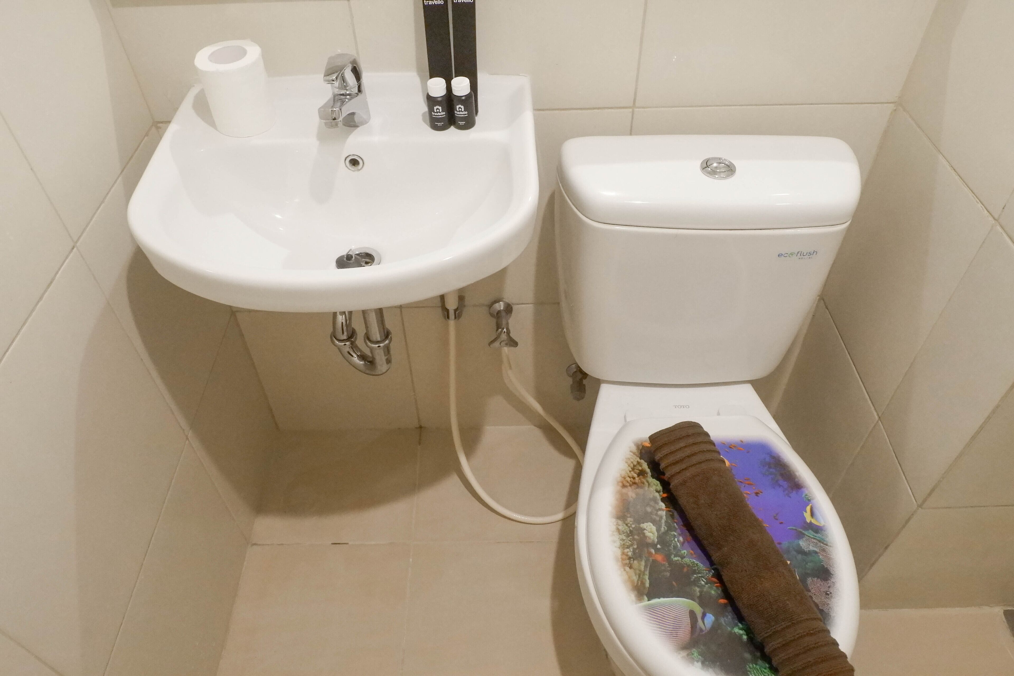 A bathroom with a white sink, toilet, and a roll of toilet paper.