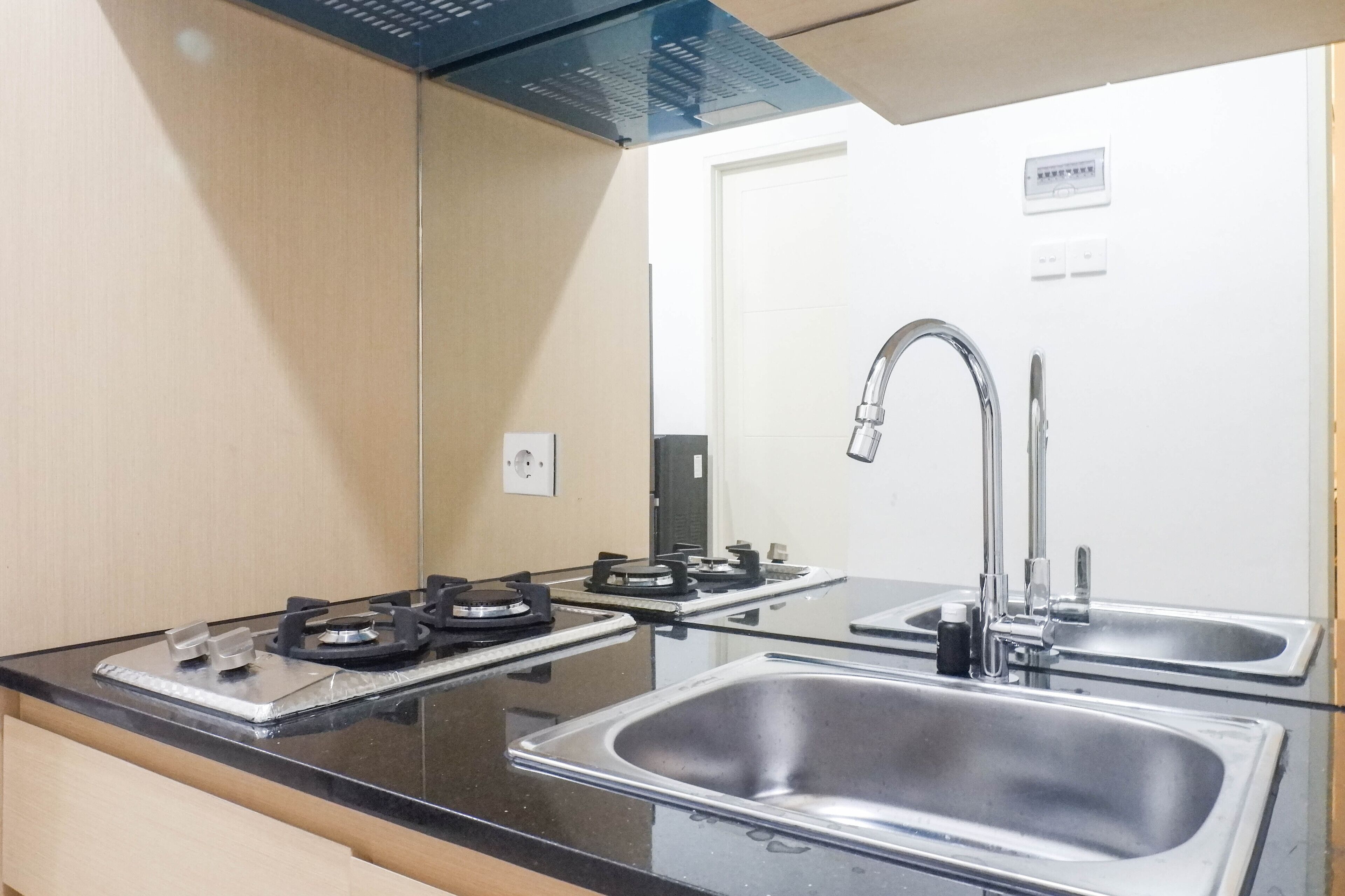 A modern kitchen with a gas stove, stainless steel sink, and a mirror above the countertop.