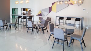 A modern conference room with glass tables and chairs, geometric wall art, and pendant lighting.
