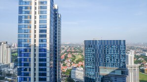 A high-rise building with a modern glass facade, surrounded by other buildings and a view of a cityscape.